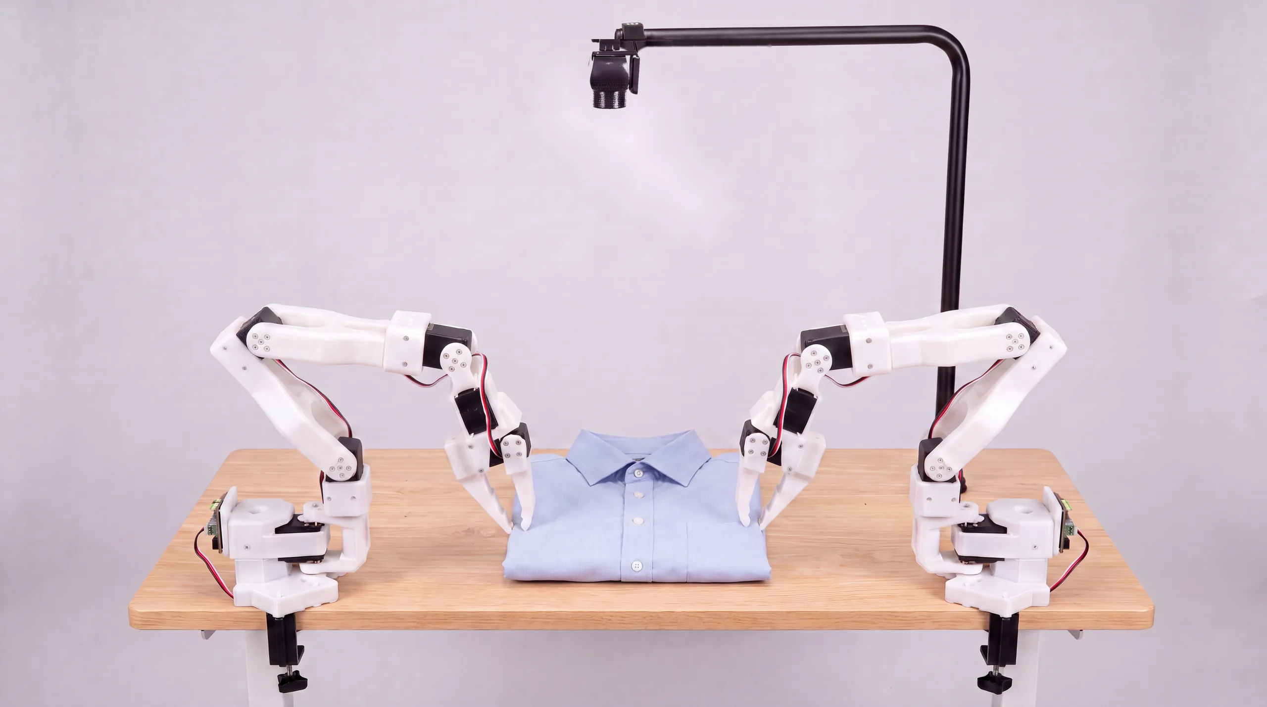Robot arms squaring a folded dress shirt on the table