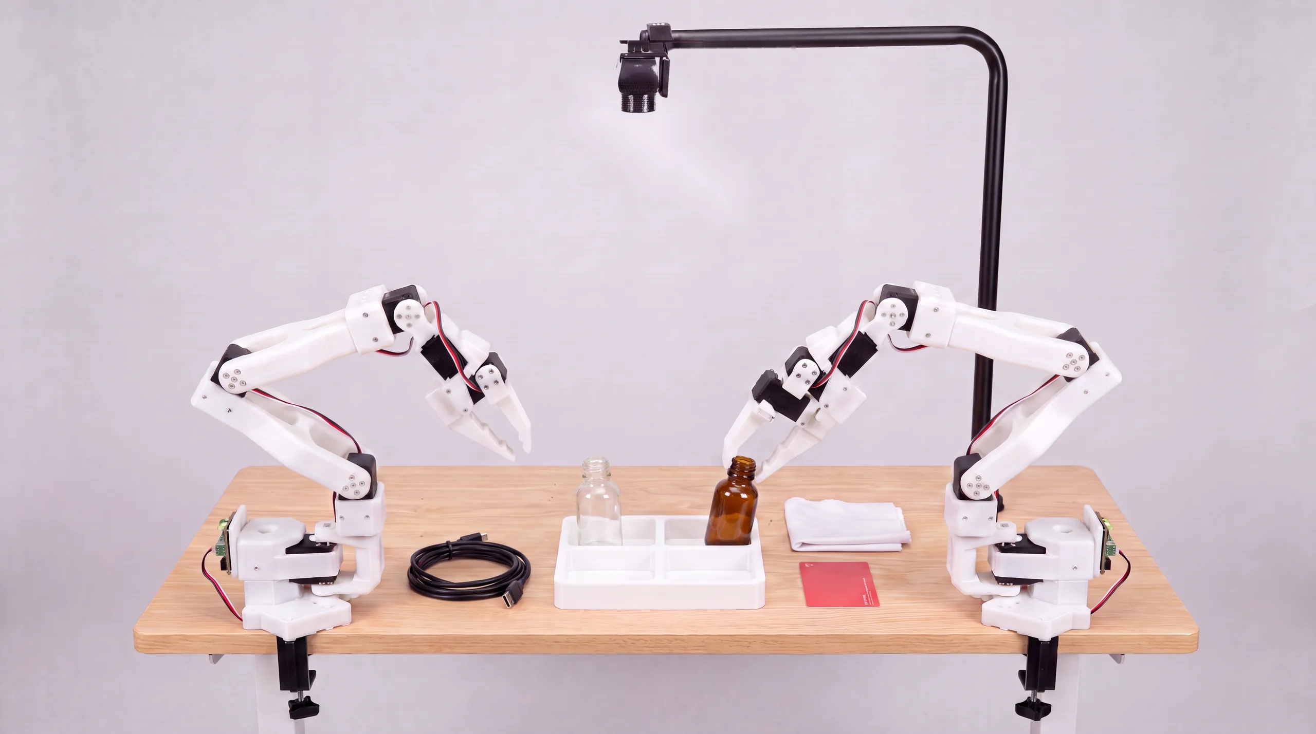 Robot arms placing bottles into a kitting tray insert